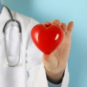 female doctor with stethoscope holding red heart 6WZMDZL