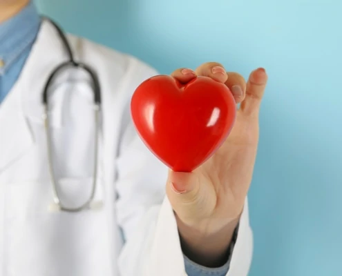 female doctor with stethoscope holding red heart 6WZMDZL